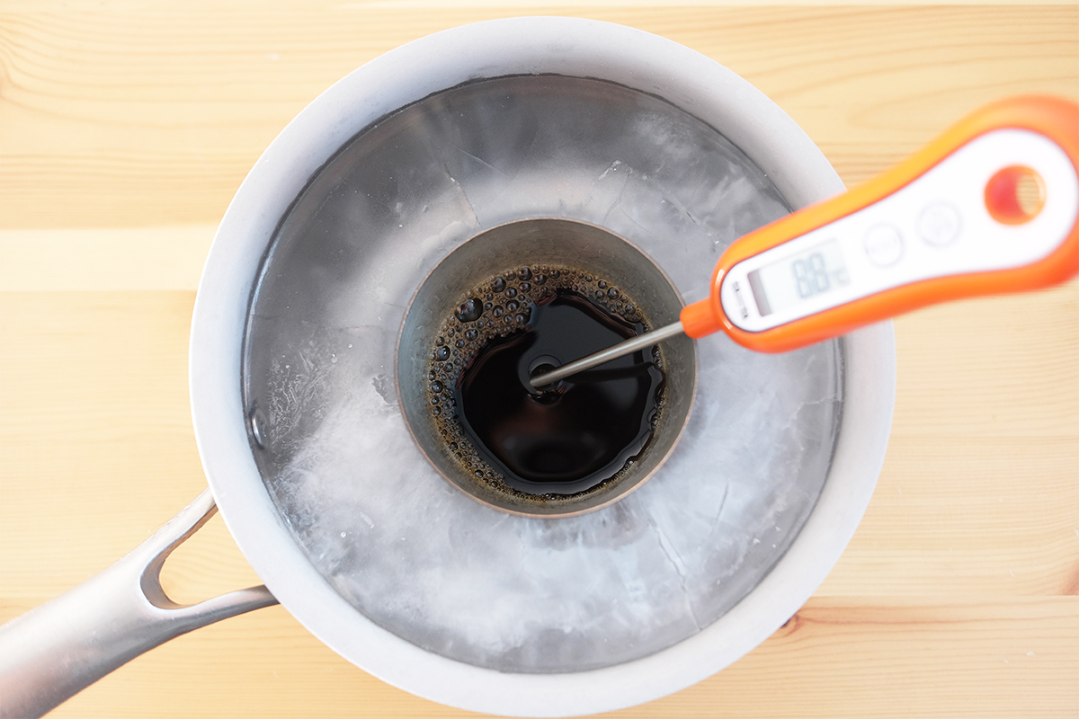 氷を張った小鍋に入ったコーヒーが入ったタンブラーと温度計